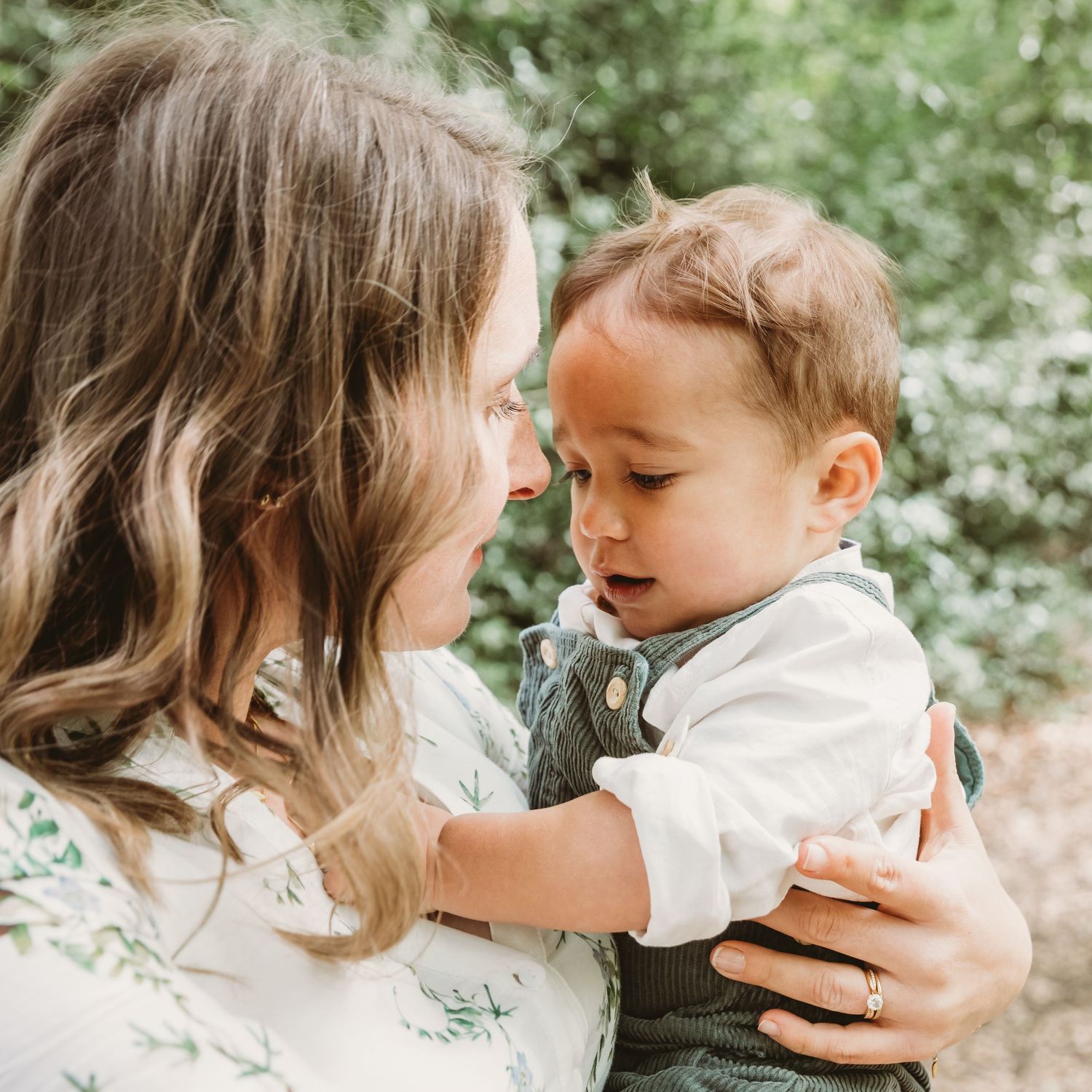 Mother and child share a tender moment together in a sunlit outdoor setting.