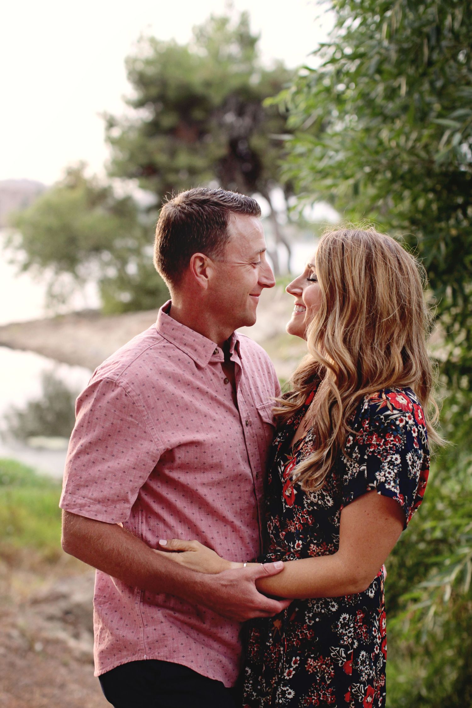 A couple sharing a romantic moment on a hillside path during golden hour.