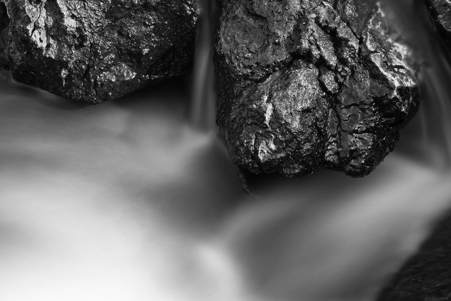 Long exposure black and white image of water rushing between rocks at McCormick's Creek State Park in Spencer, Indiana.