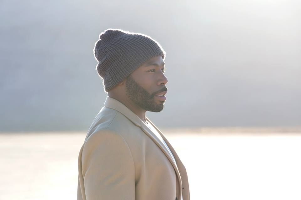 Person in winter coat and beanie looking sideways against misty background.