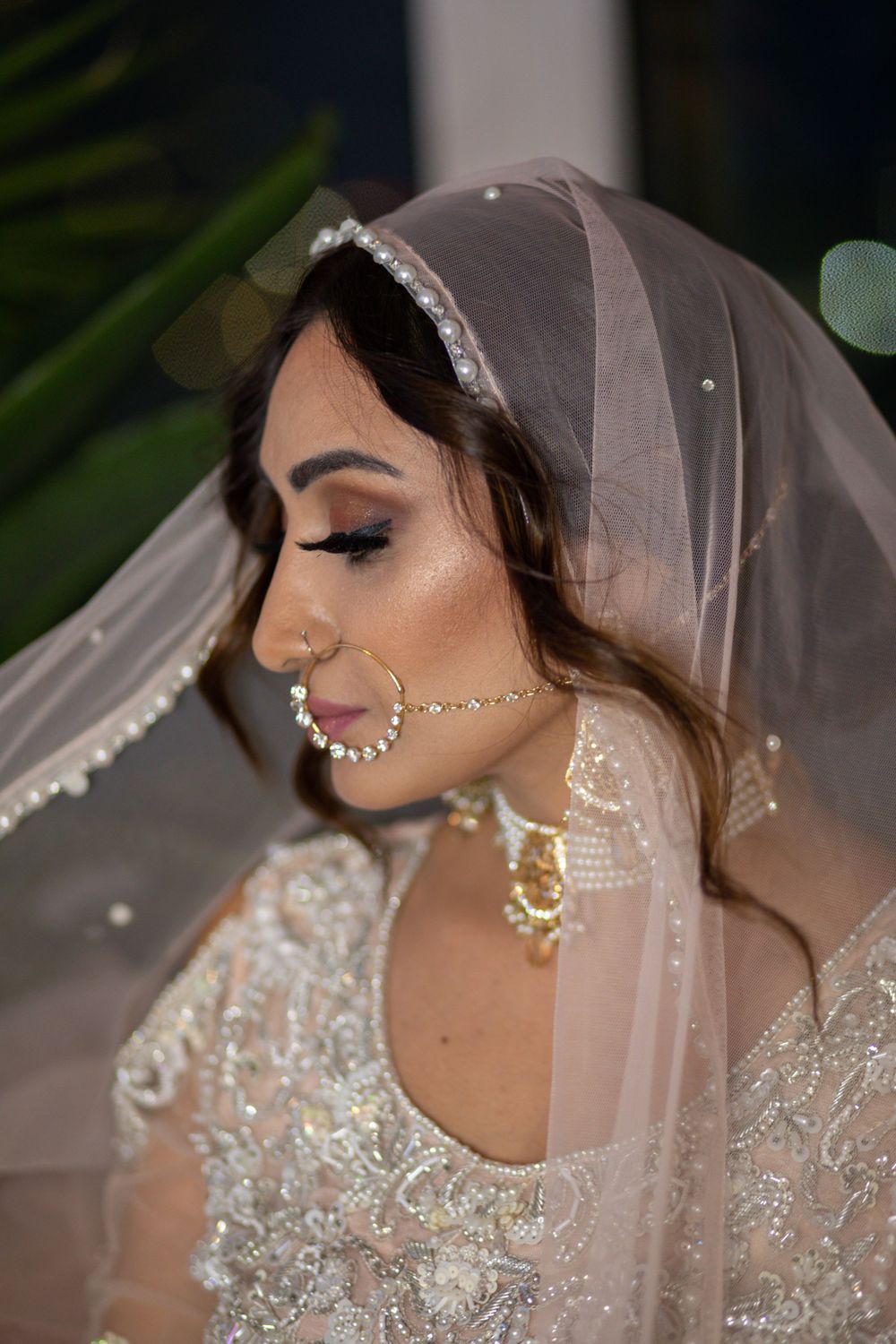 Side profile of a bride in a sheer veil with beaded trim and elegant South Asian bridal jewelry.