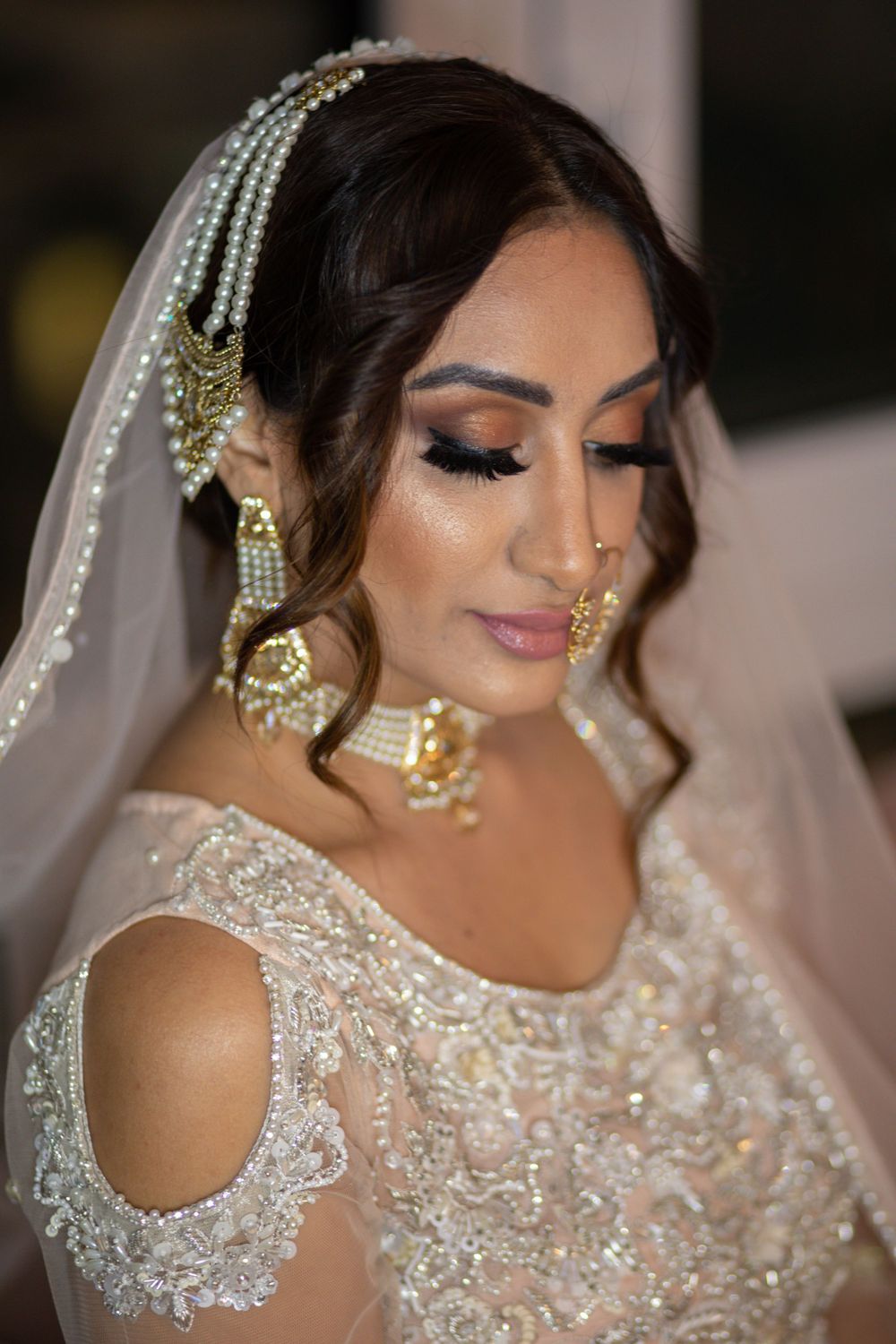 South Asian bridal portrait showcasing elaborate jewelry, embroidered dress and traditional wedding makeup.