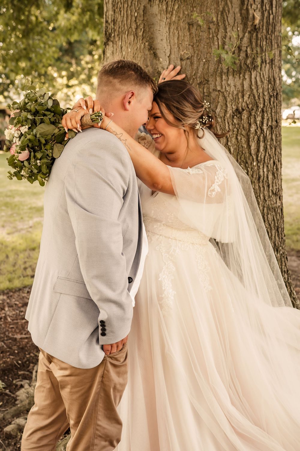 bide and groom share a tender embrace in park afer wedding