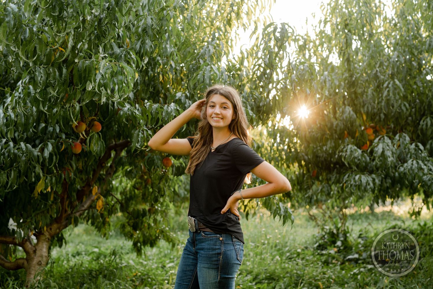 Portrait in a peach orchard during golden hour with sunlight filtering through the trees.