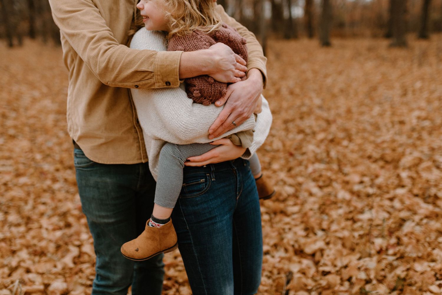 Candid autumn family moment with warm tones and fallen leaves.