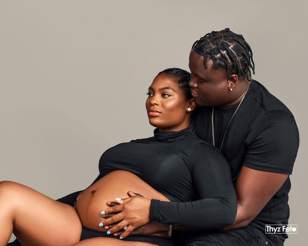 Emotional maternity photoshoot of a couple, with the partner kissing the expectant mother’s baby bump.