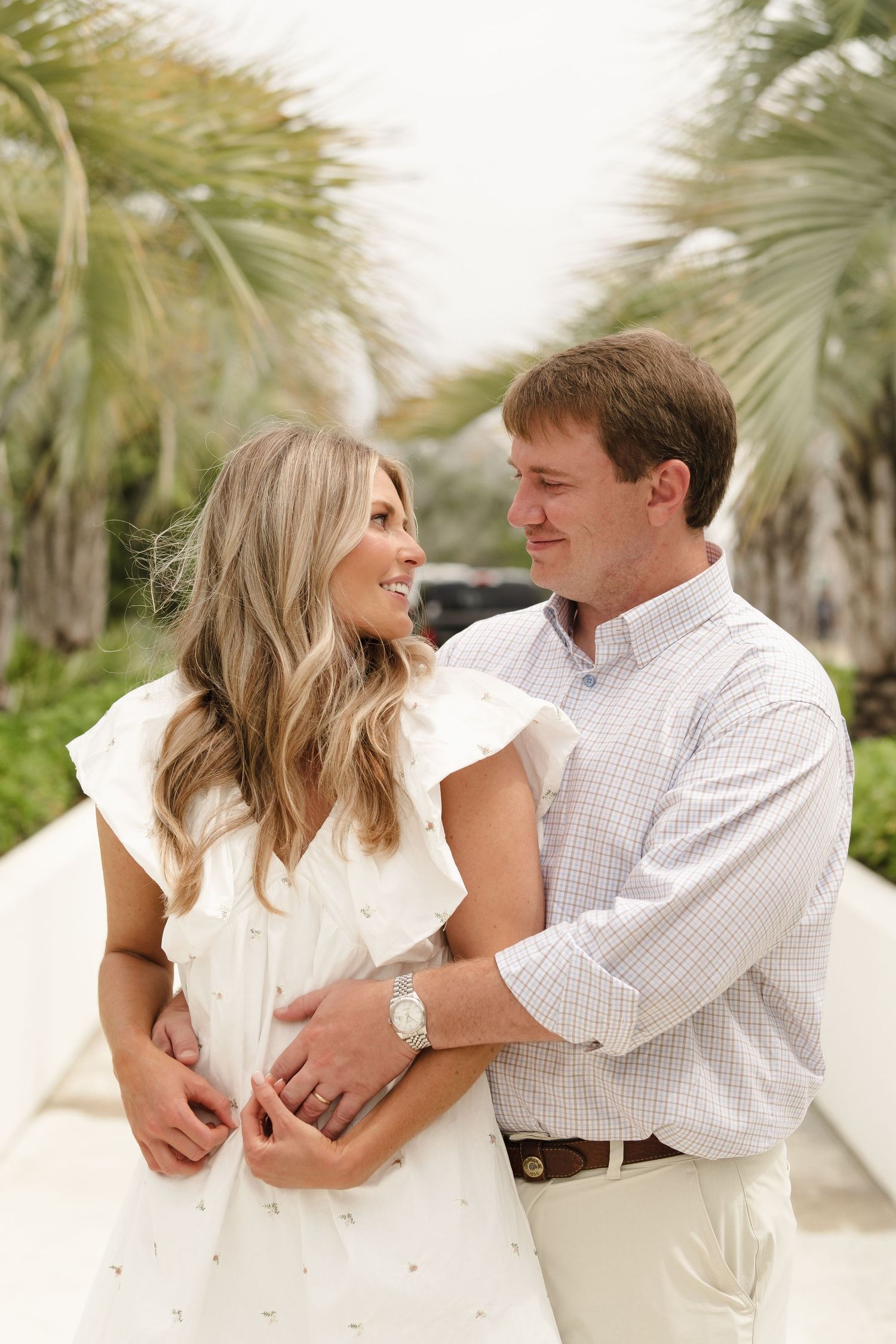 A romantic couple embraces against a backdrop of palm trees in a series of candid moments.