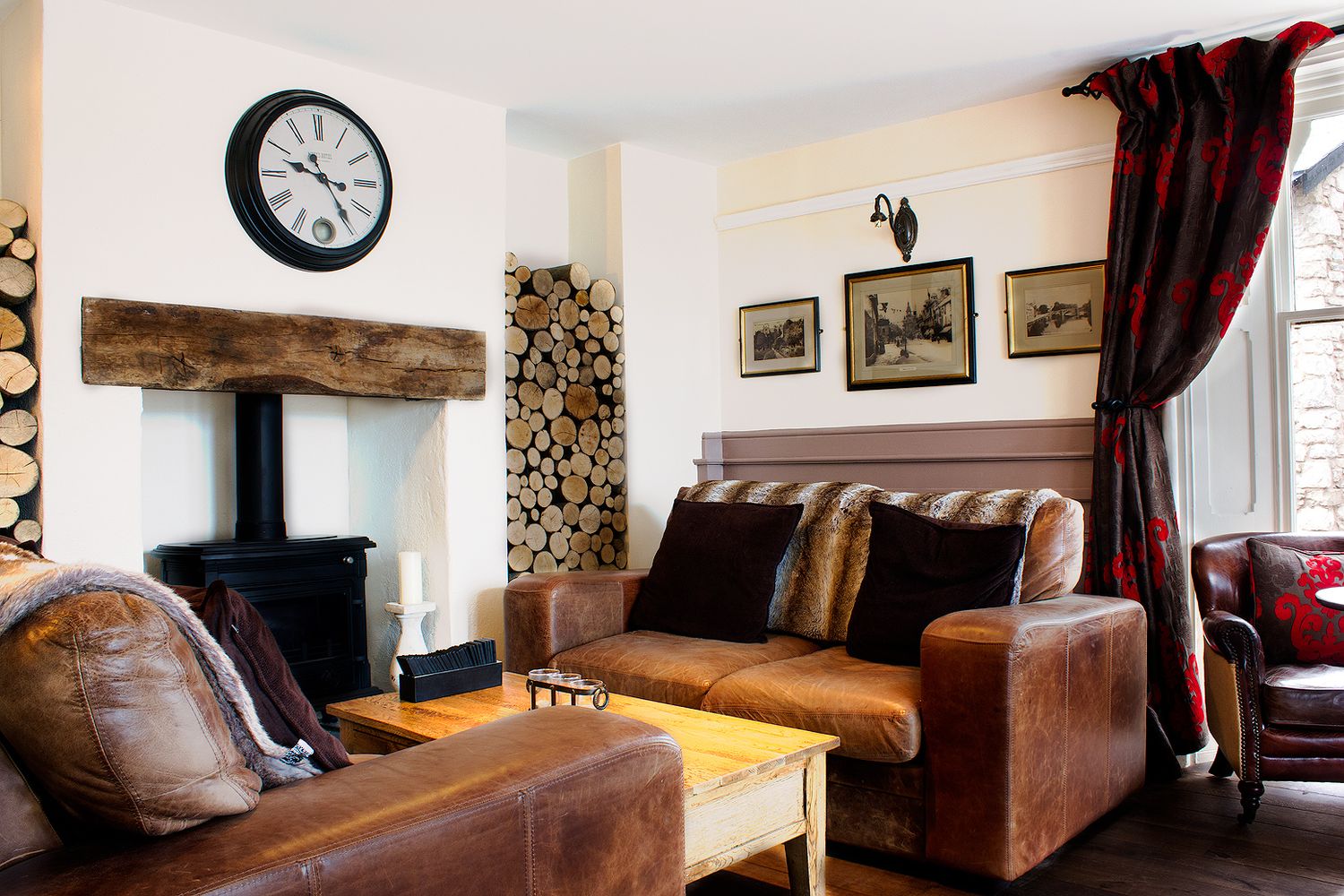 Cozy living room interior with leather sofa, wooden beam mantel, and rustic decor.