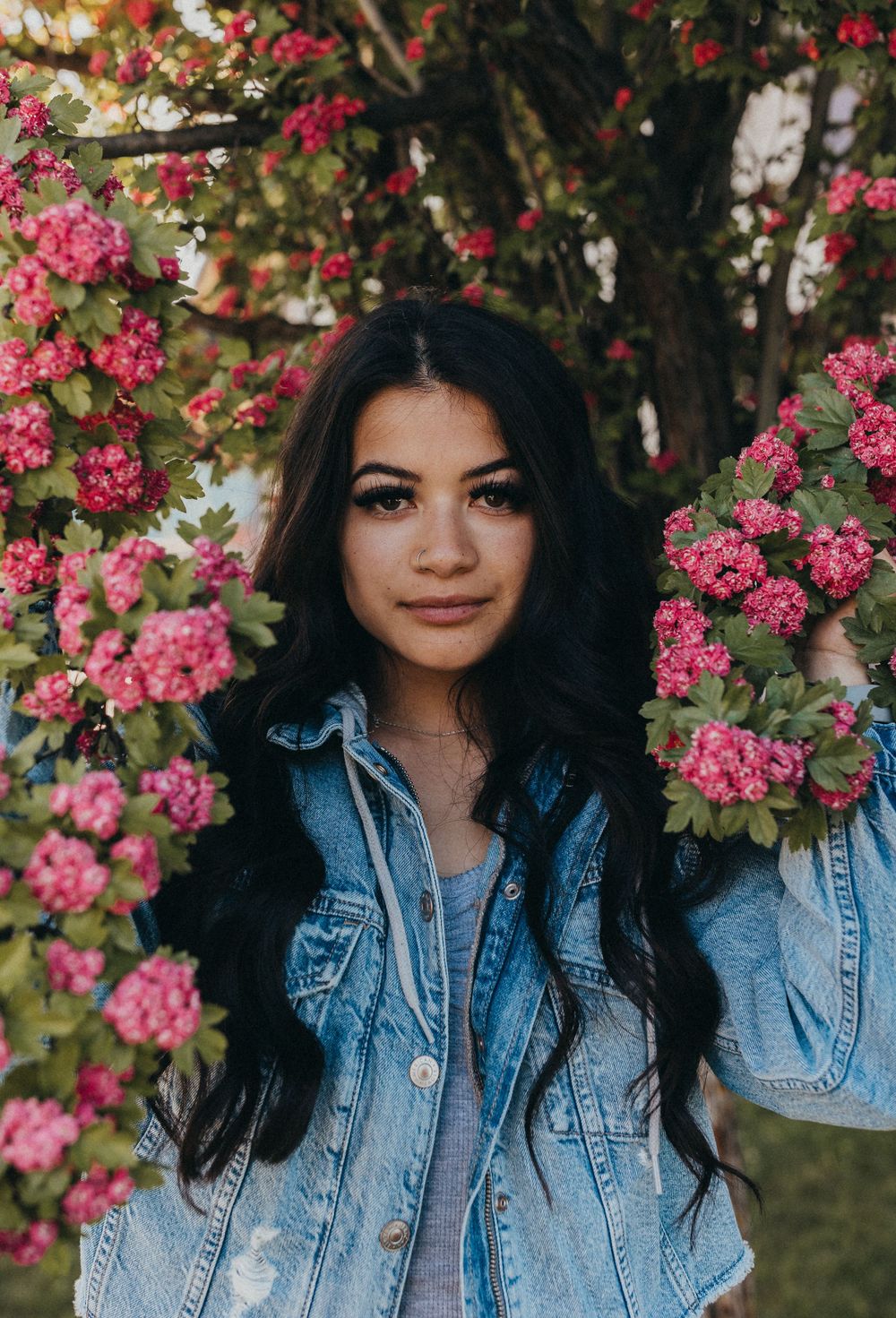 Portrait among pink flowering bushes and denim jacket.