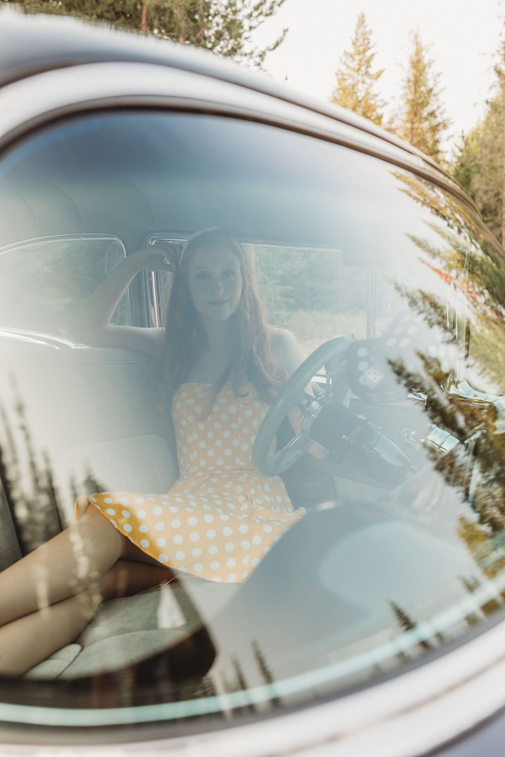 View through vintage car window of someone in polka dot dress.