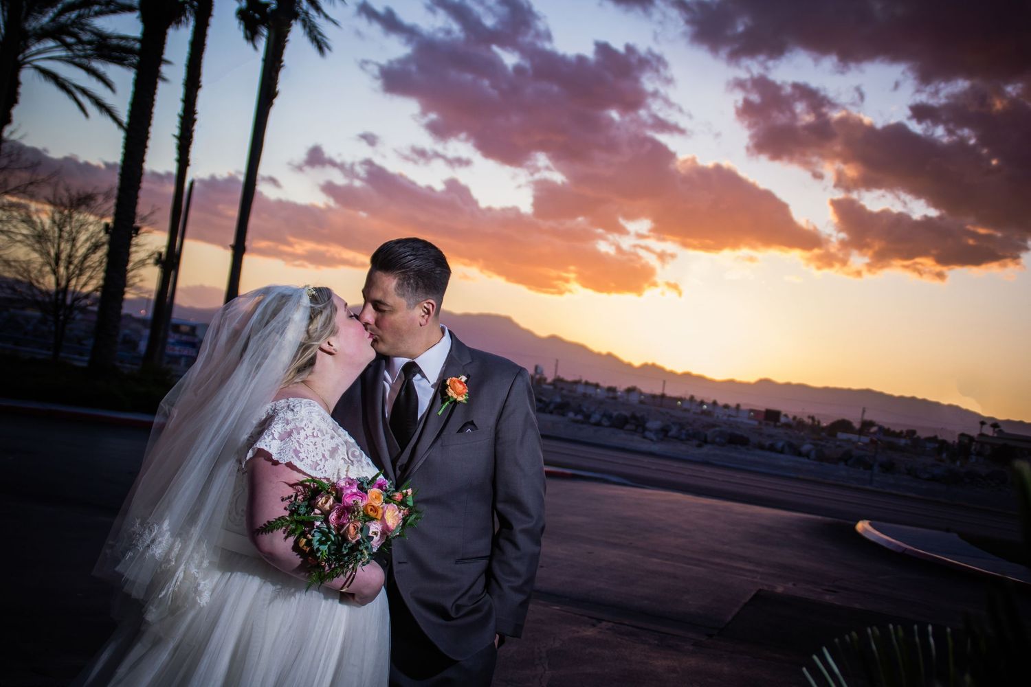 Sunset wedding portrait with palm trees and dramatic purple sky in background.
