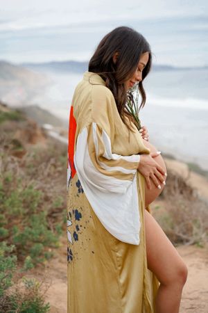 Person in flowing floral kimono standing on coastal cliff overlooking the ocean.