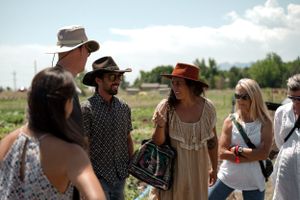 Group gathered outdoors wearing sun hats and summer clothing in bright sunlight.