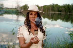 Atmospheric scene by a lake with smoke wisps and a wide-brimmed hat.