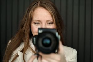 Close-up shot of photographer holding professional camera with white background.