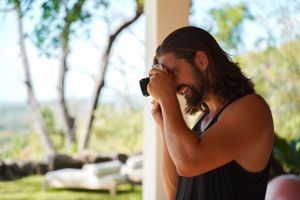 Photographer with long hair taking photos outdoors using a professional camera.