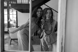 Black and white reflection of two people taking photos in a mirror.