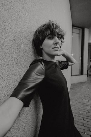 Black and white portrait against a textured wall in an urban setting.