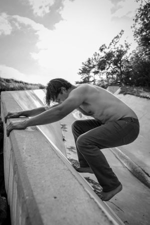 Black and white photo of a skateboarder performing a trick on a ramp outdoors.