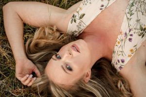 Creative portrait of a person lying in grass wearing a floral dress.
