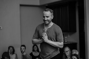Black and white image of speaker gesturing during presentation to audience.
