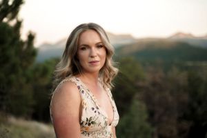 Portrait taken at sunset against a mountain backdrop wearing a floral dress.