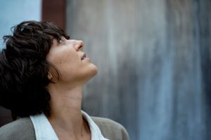 Artistic profile portrait showing someone looking up against a blurred background.