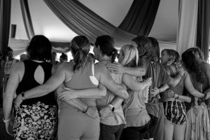 Black and white photo of people embracing in a circle showing unity and connection.