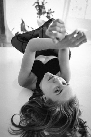 Artistic black and white boudoir photo with dramatic pose and plant shadows.