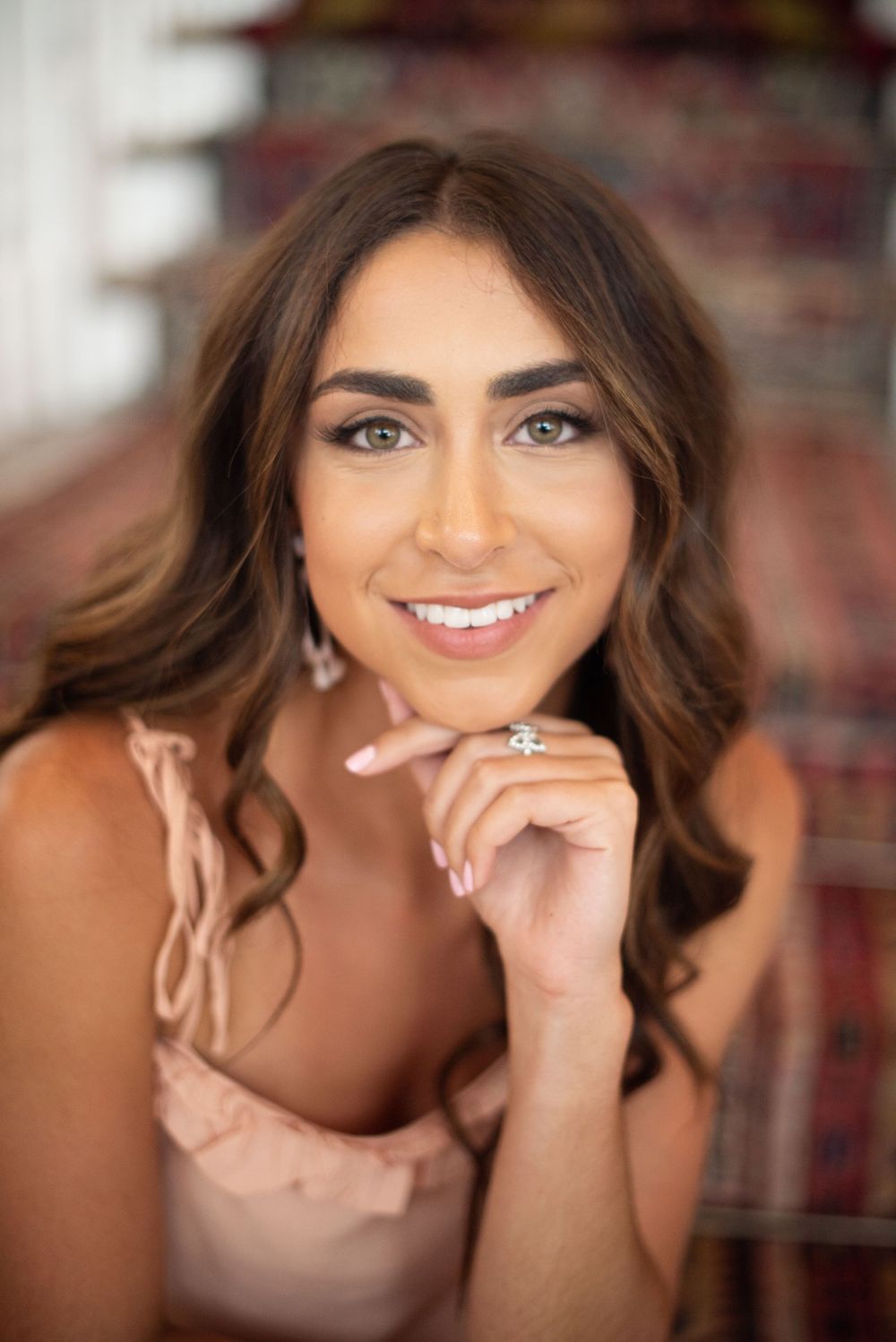 Portrait photograph featuring soft makeup and jewelry against blurred background.