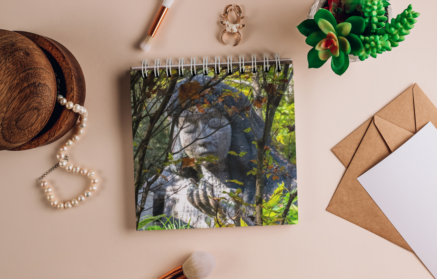Flatlay photography setup with notebook, decorative items and botanical elements on a wooden surface.