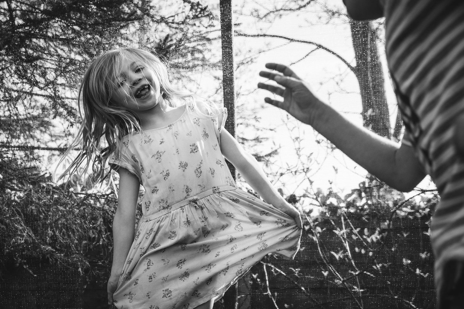 Black and white photo capturing a playful moment of joy and laughter in a forest setting.