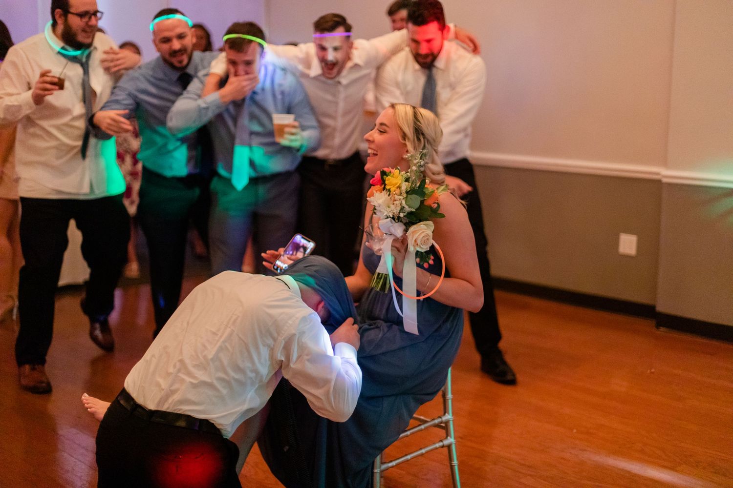 Wedding guests dancing and celebrating at a lively indoor reception party.