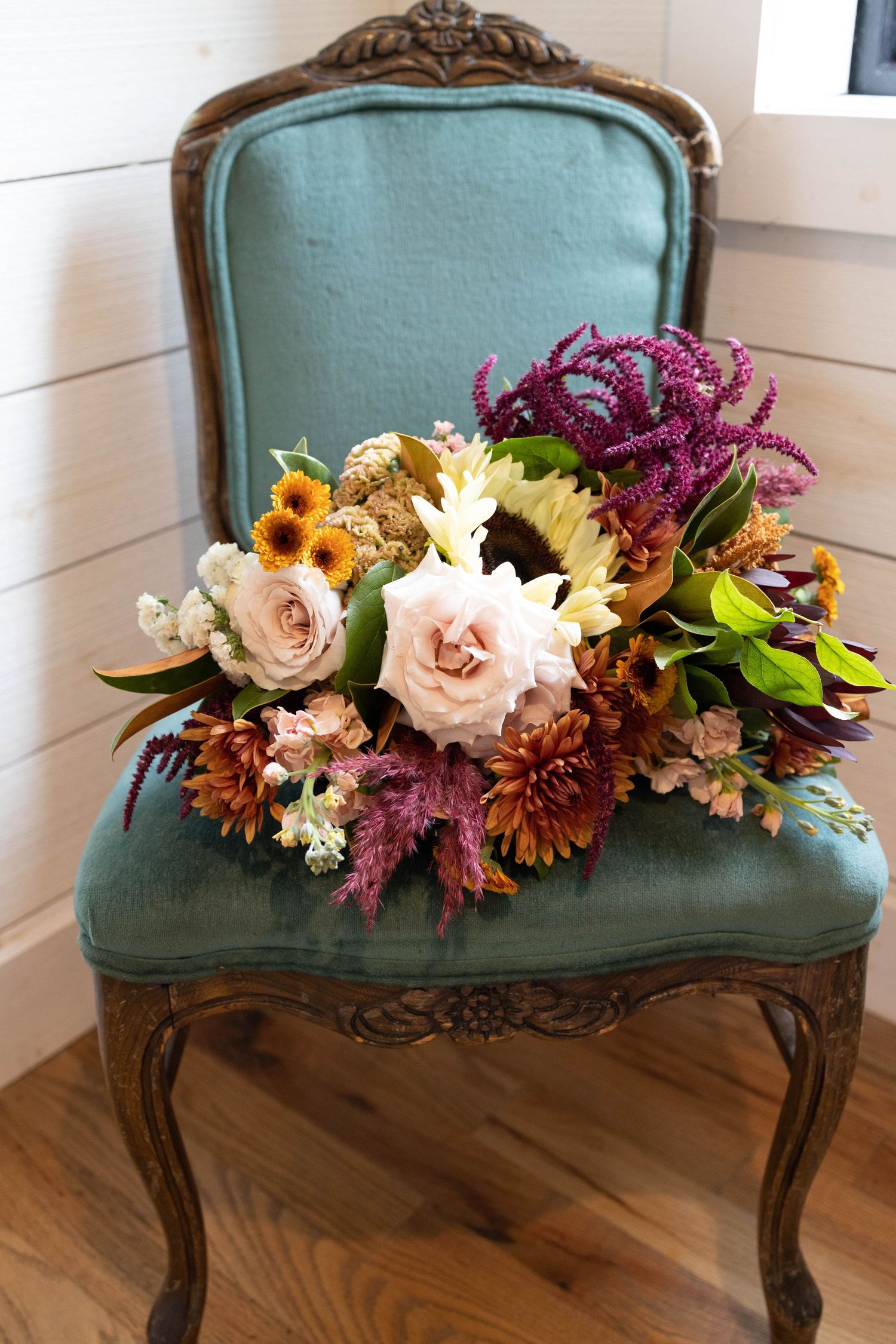 A stunning bridal bouquet sits on a velvet chair