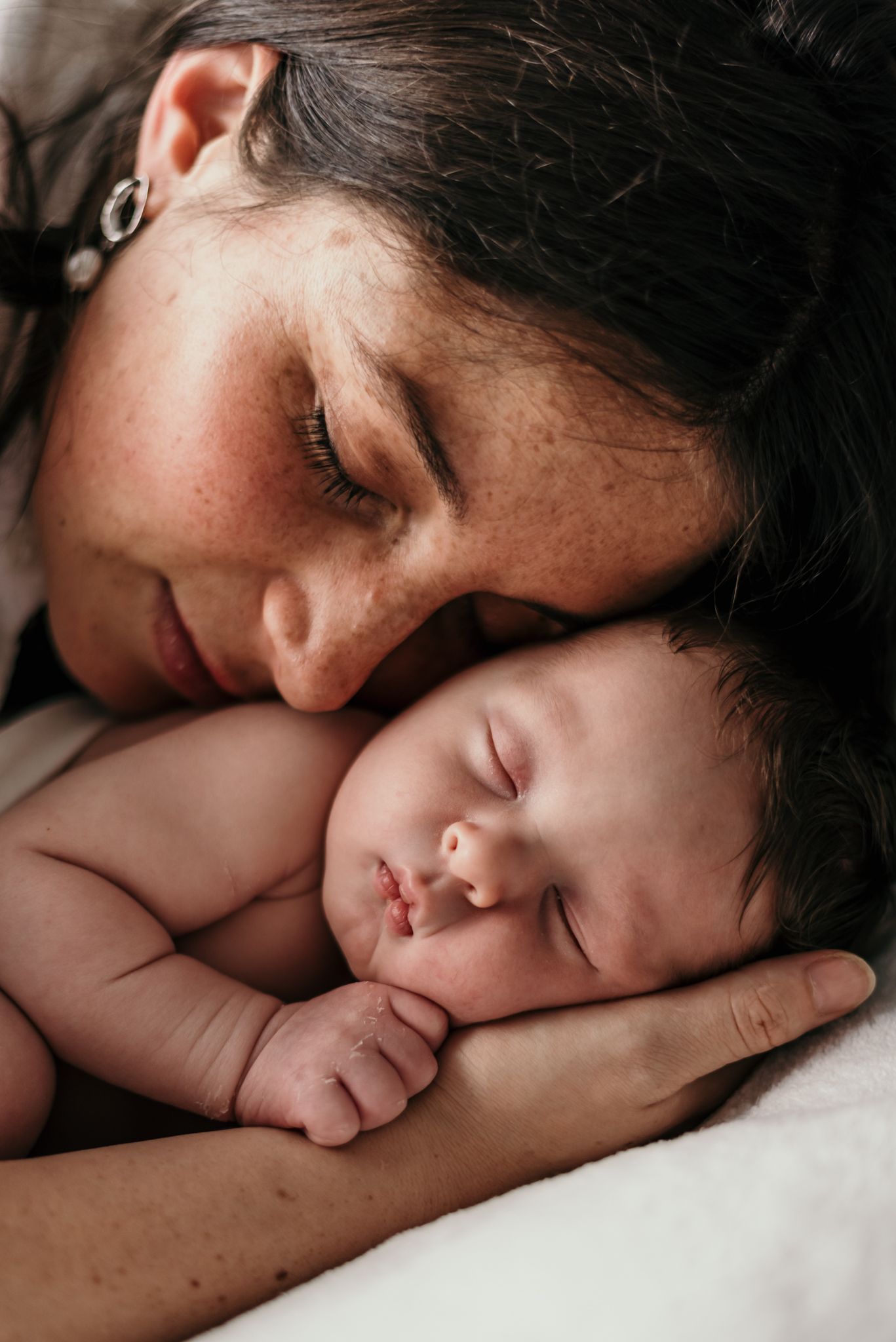 Close-up portrait of gentle bonding moment with sleeping infant.