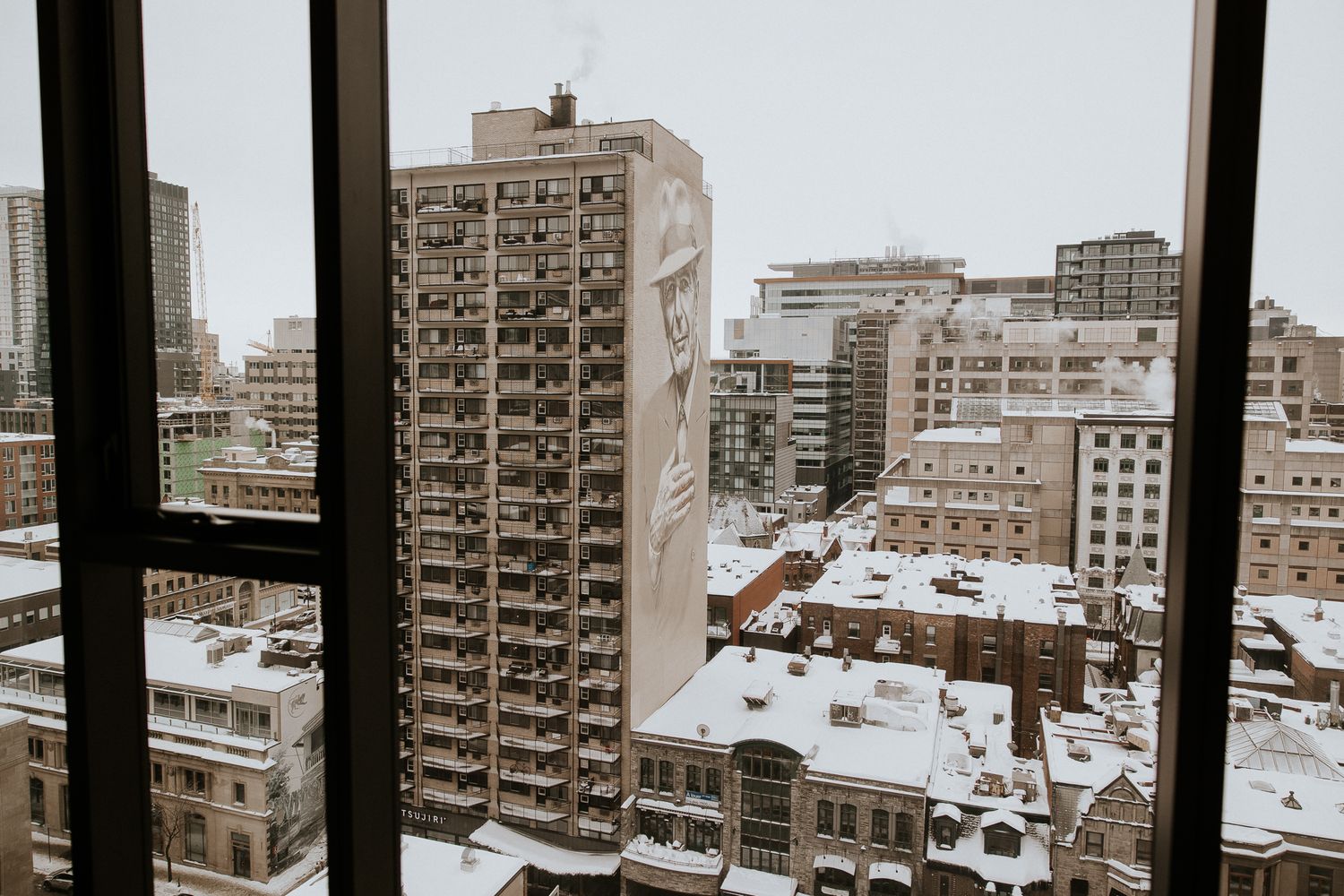 Snowy winter cityscape viewed through hotel window on wedding day in urban downtown setting.