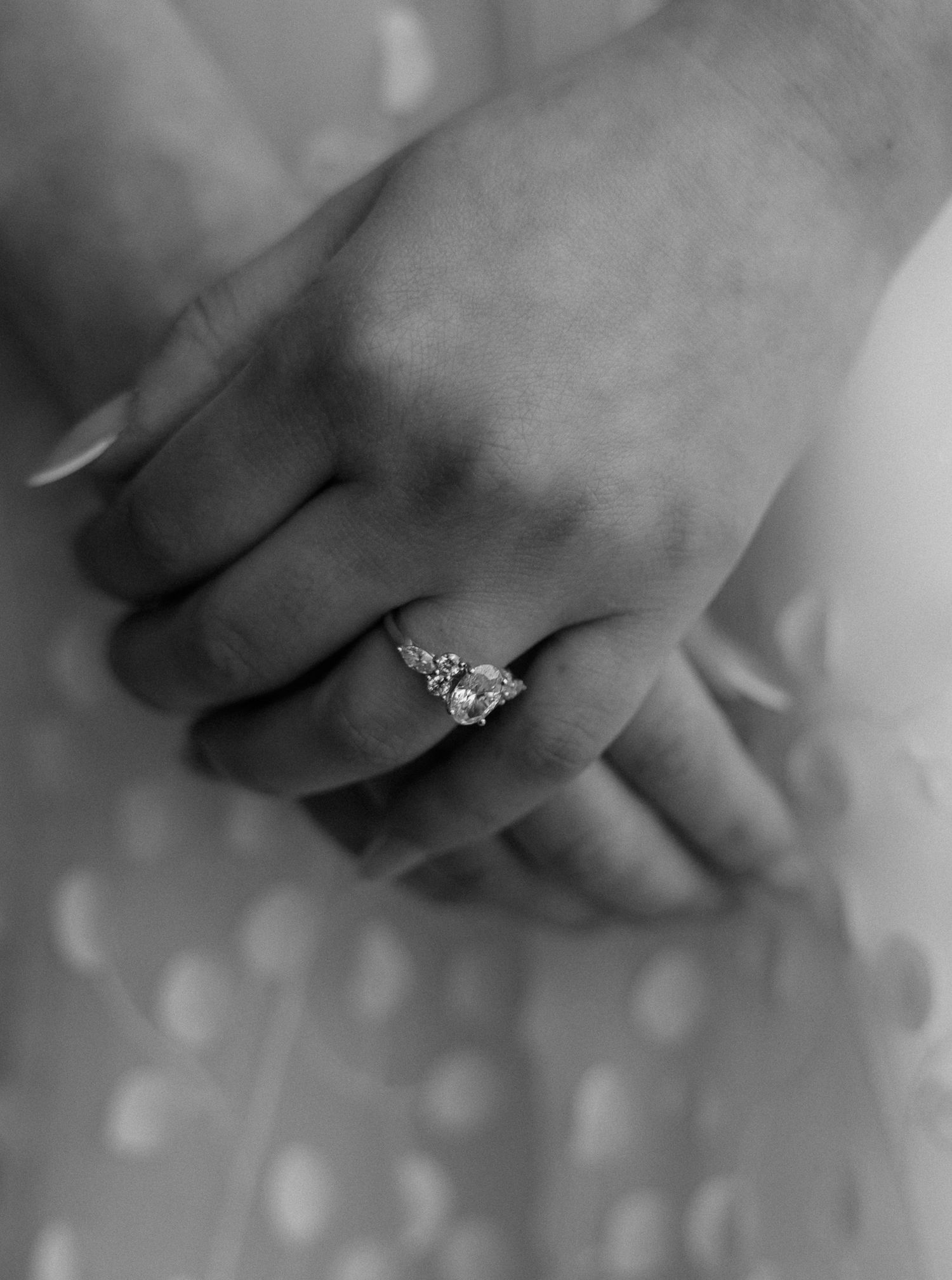 Close-up black and white photo of elegant diamond engagement ring on bride's hand.
