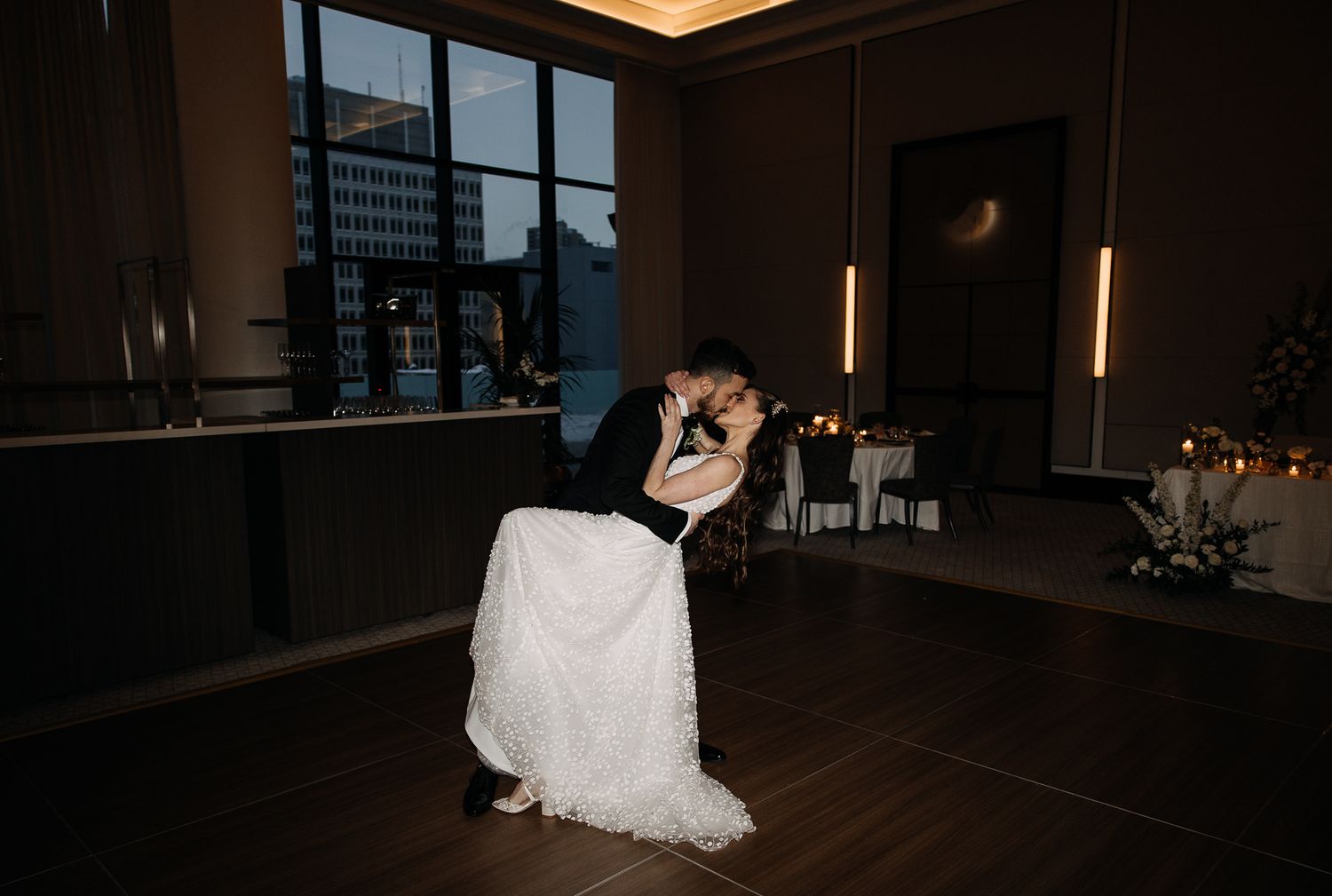 Bride and groom sharing a passionate dip kiss during their first dance at reception.