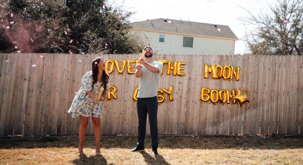 Yellow balloon letters mounted on a wooden fence create a festive outdoor display.