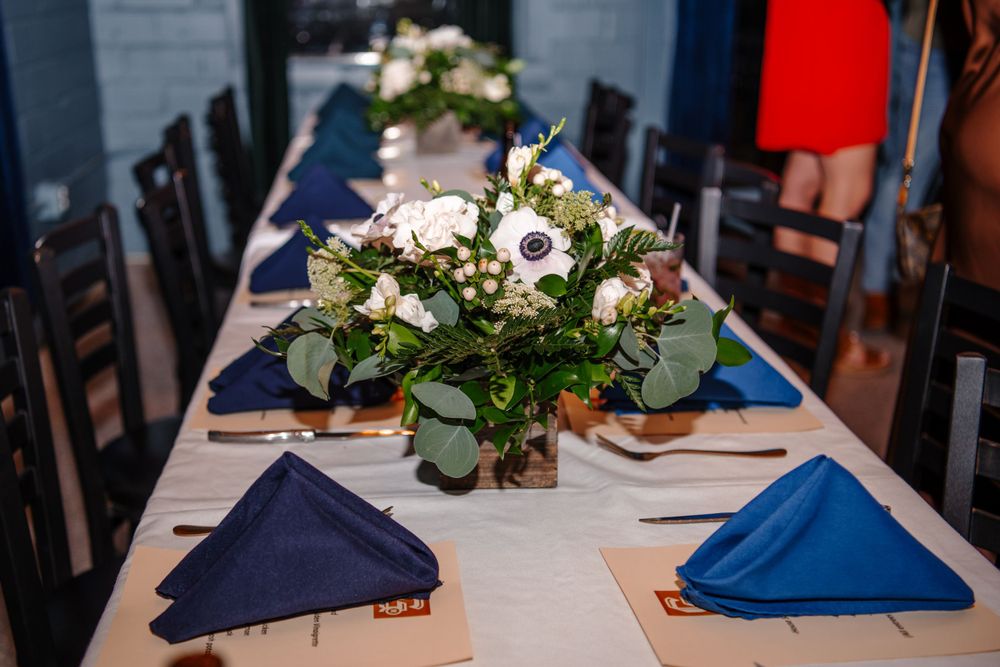 Elegant table settings with floral arrangements and blue napkins at a formal event.