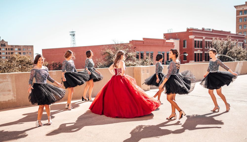 Dynamic group pose with flowing dresses against an urban rooftop background.