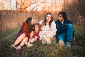A family sharing a relaxed moment together in a field during golden hour.
