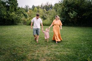 A carefree summer moment as three people walk hand-in-hand through a lush green meadow.