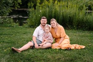 A tender family moment captured on a grassy lawn with wildflowers in the background.