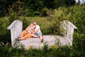 A romantic summer scene on a rustic wooden bridge surrounded by wildflowers and tall grass.