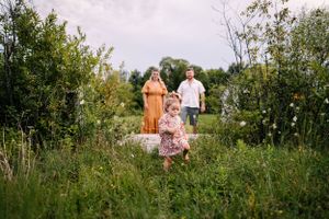 A candid outdoor family photoshoot in a lush green meadow on a summer day.