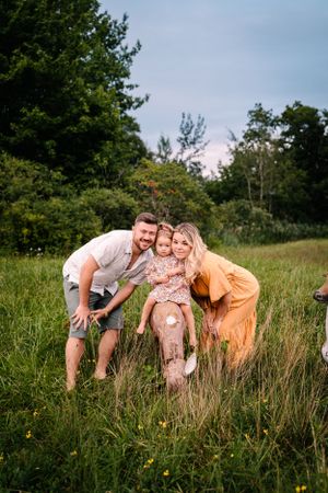 A joyful moment captured in long grass with coordinated outfits in orange and white tones.