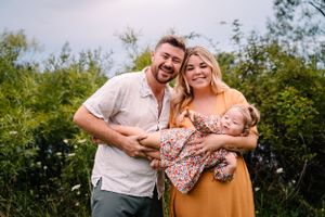 A warm outdoor portrait of a family wearing coordinating orange and white outfits.