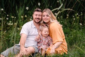 A relaxed family photo session in a natural meadow setting with wildflowers.