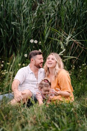 A candid family moment shared in tall grass and wildflowers during golden hour.